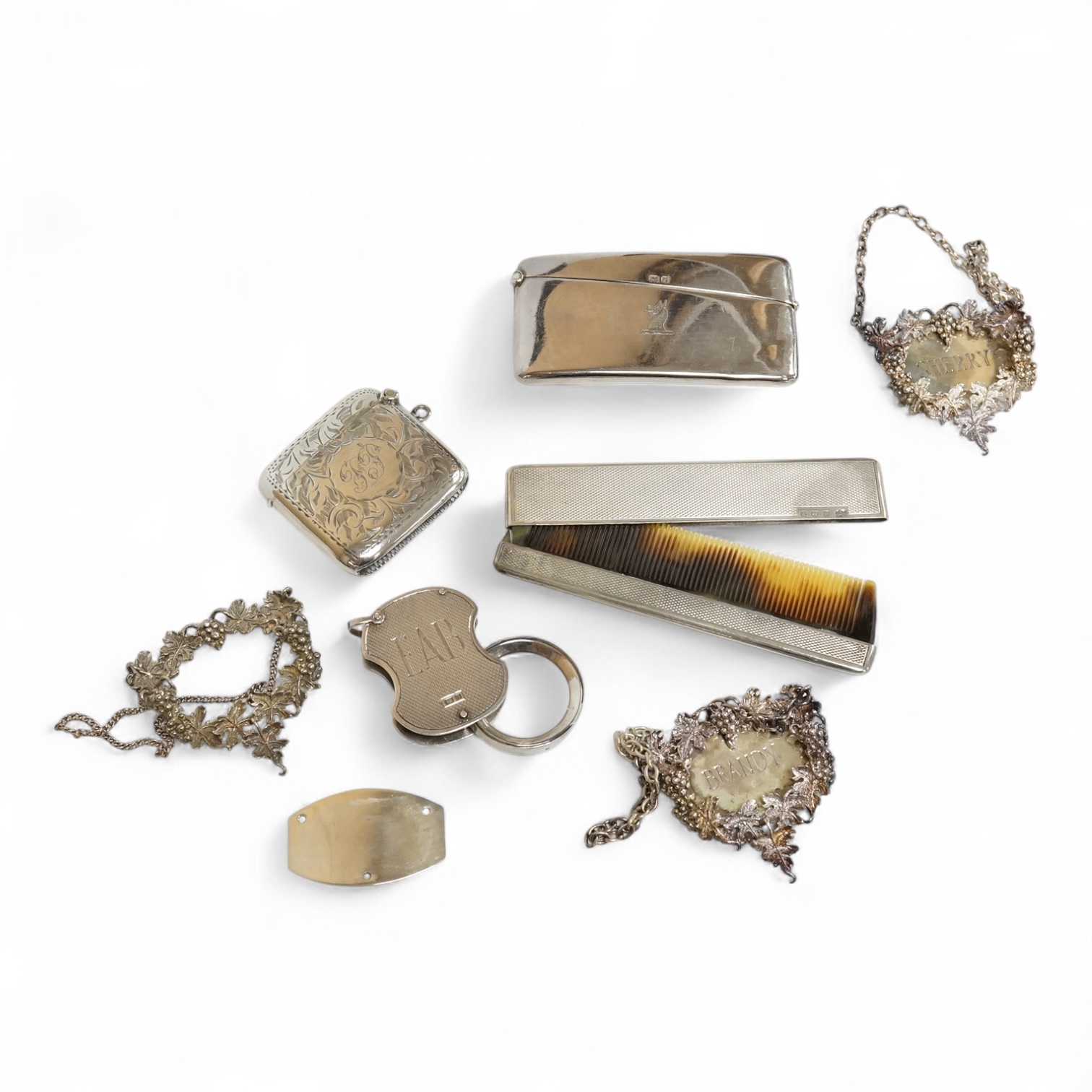 A small group of collectable silver including an Edwardian card case, a set of three modern silver wine labels with applied fruiting vine border, one a.f. London, 1975, a vesta case, travelling comb and folding eye glass